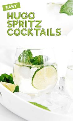 two glasses filled with water and limes on top of a white plate next to ice