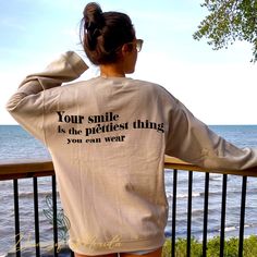 a woman wearing a sweatshirt that says your smile is the prettiest thing you can wear