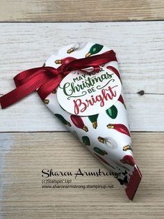 an ornament shaped like a christmas heart on top of a wooden table with red ribbon