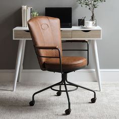 a brown leather office chair sitting in front of a desk with a laptop on it