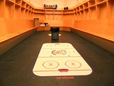 an indoor hockey rink with no skaters on the floor and two black trash cans in the center