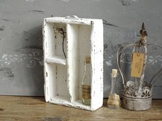 an old white box with some bottles in it on a wooden table next to other items