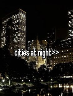 the words cities at night are lit up in front of some buildings and trees with lights on them