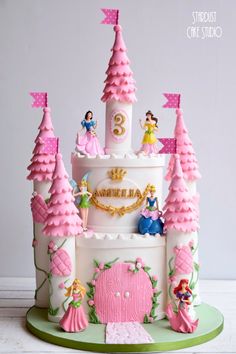 a princess castle cake with pink frosting and decorations on the top, surrounded by trees