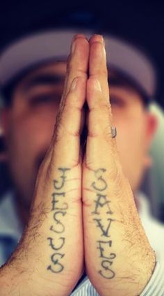 a man holding his hands together with two small tattoos on their palms