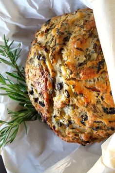 a piece of bread sitting on top of a white paper covered in cheese and herbs