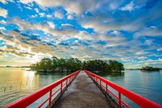 the red bridge is going across the water to an island in the distance with trees on both sides