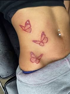 a woman's stomach with three pink butterflies on her side and the bottom part of her abdomen