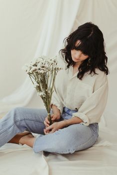 a woman sitting on the floor holding flowers