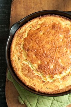 a baked dish in a cast iron skillet on a wooden cutting board with green leaves