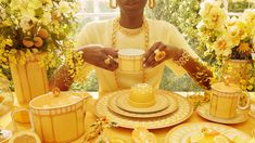 a woman is sitting at a table with yellow dishes and flowers in front of her