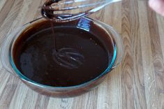 someone pouring chocolate into a glass bowl with whisk attachments on the side