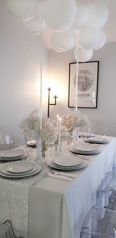 the table is set with plates, silverware and white flowers in vases on it