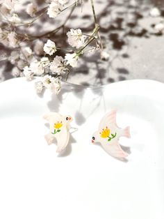 Handmade craft stud earrings of lovely doves flying birds and flowers, symbolizing love, peace, purity, and friendship. I turn all the positive emotions into wearable art pieces and hope they can bring good luck to people who wear them.  Main Material: Shrink plastic Main color: White and red Shape: Flying bird Size：1.7* 1.9 cm Occasion: Any Style: Casual, cute, fantasy. Work hours: Handmade for 1.5 hours. 7 variations in total.  See variations and annotations in the last picture. White Bird-shaped Jewelry Gift, Whimsical Bird Design Earrings For Gift, Doves Flying, Dove Flying, Cute Craft, Birds Design, Flying Birds, Craft Jewelry, Bird Earrings