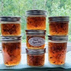 four jars filled with food sitting on top of a window sill