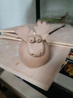 a clay moose head sitting on top of a table with chopsticks in it's mouth