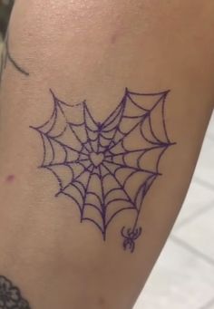 a spider web tattoo on the leg of a woman's arm, showing it is purple