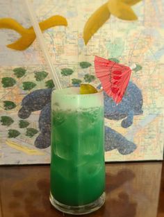 a green drink with an umbrella on the top sits on a table in front of a map