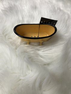 a black and yellow bowl sitting on top of a white fur covered floor