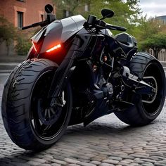 a black motorcycle parked on top of a cobblestone road