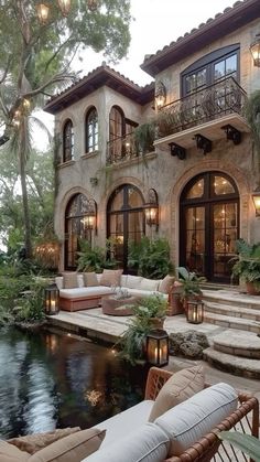 an outdoor living area with couches and tables next to a pool in front of a house