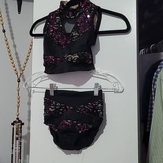 two pieces of clothing are hanging on a clothes rack next to a beaded necklace