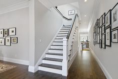 the stairs in this house are white and have black frames on each side, along with framed pictures