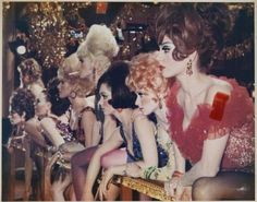 a group of women sitting next to each other in front of a christmas tree with lights