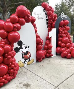 red balloons shaped like mickey mouse are on display at the entrance to an amusement park