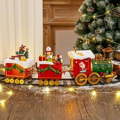 a christmas train with santa claus and other decorations on the track next to a christmas tree