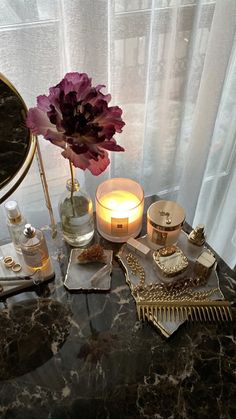 a table topped with candles and other items on top of a marble counter next to a window