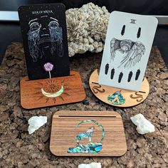 three wooden coasters sitting on top of a table next to some rocks and flowers