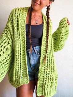 a woman wearing a green knitted cardigan with braids in front of her face