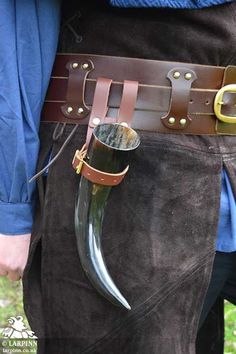 a close up of a person wearing a leather belt and holding a large horn in his pocket