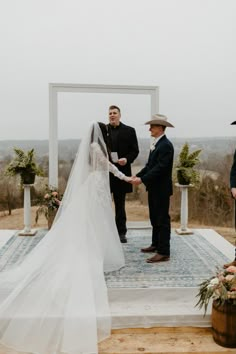 a bride and groom standing at the end of their wedding ceremony with an arch in the background