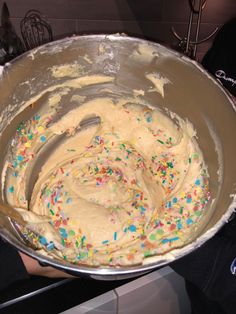 a cake batter in a metal bowl with sprinkles on the top and bottom