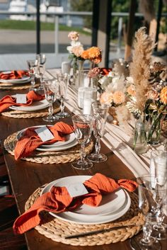 the table is set with orange napkins and place settings