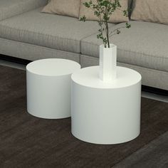 two white round tables sitting in front of a couch