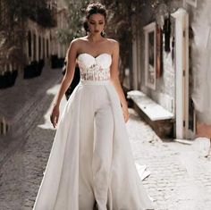 a woman is walking down the street wearing a white dress and high - waisted pants