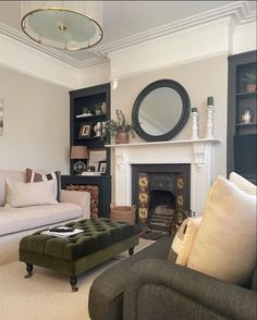 a living room filled with furniture and a fire place in front of a mirror on the wall