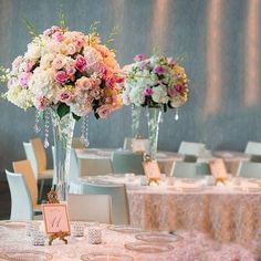 two tall vases filled with pink and white flowers on top of a round table