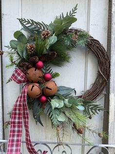 a wreath with pine cones, berries and greenery hangs on the front door of a house