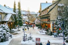 people are walking down a snowy street lined with shops