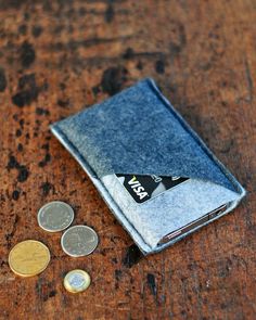 a small wallet sitting on top of a wooden table next to two coins and one coin