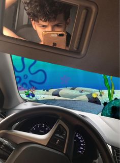 a young boy is looking at his cell phone while driving in front of an aquarium