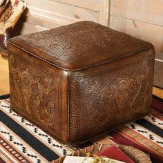 a brown leather ottoman sitting on top of a rug next to a basket and book