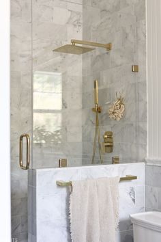 a bathroom with marble walls and flooring, including a gold shower faucet