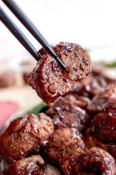 chopsticks holding up meat in a bowl