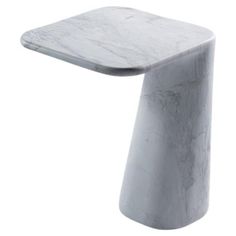 a white marble side table with one leg extended and the other end turned down to look like an object