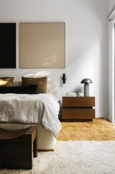 a bedroom with a bed, nightstands and two paintings on the wall above it